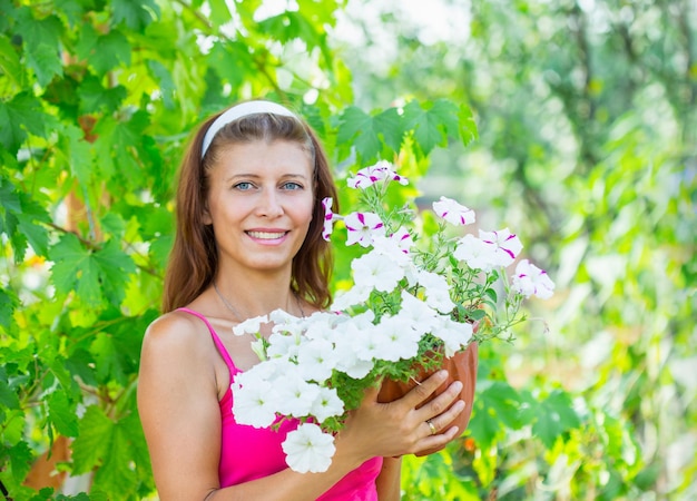 Uma mulher com um vaso de flores no jardim