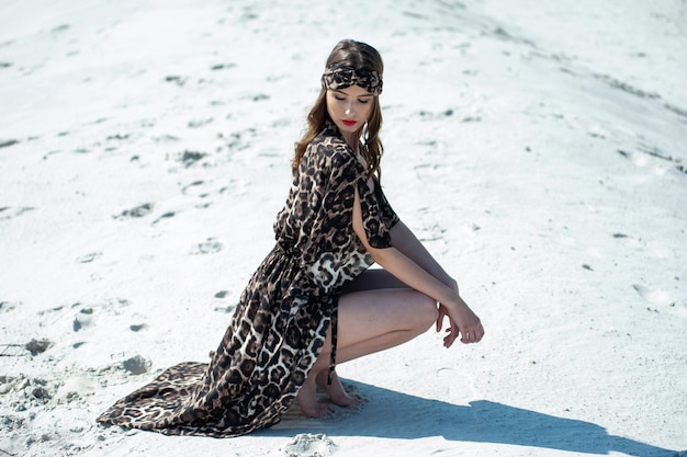 Uma mulher com um vestido estampado de oncinha posa na praia.