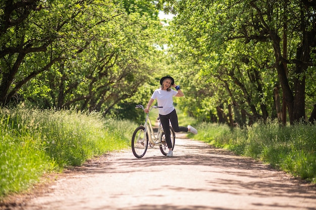 Uma mulher com uma bicicleta em uma estrada no parque