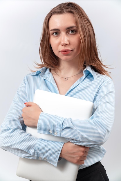 Uma mulher com uma blusa azul parada com um laptop nas mãos isolando