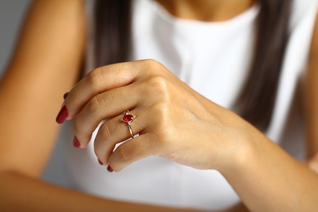 Uma mulher com uma camisa branca e uma pedra preciosa vermelha na mão