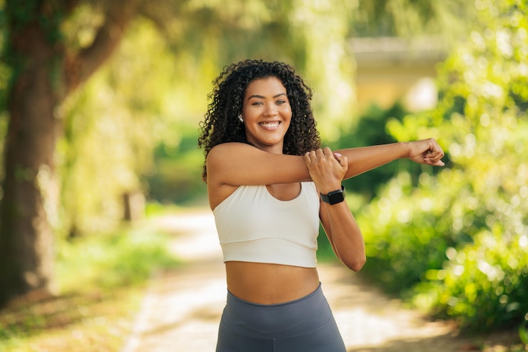 Foto uma mulher com uma camisola branca e leggings cinzentas estende o braço enquanto sorri para a câmera em um