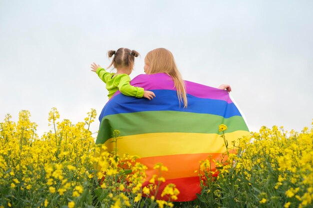 Uma mulher com uma criança nos braços e com uma bandeira LGBT desfraldada arco-íris brilhante