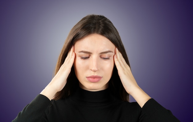 Uma mulher com uma dor na cabeça segura uma enxaqueca na cabeça