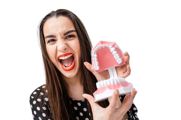 Uma mulher com uma escova de dentes e um dente falso Uma mulher com uma escova de dentes e um dente falso