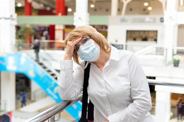 Uma mulher com uma máscara de vírus anda em um local público da cidade
