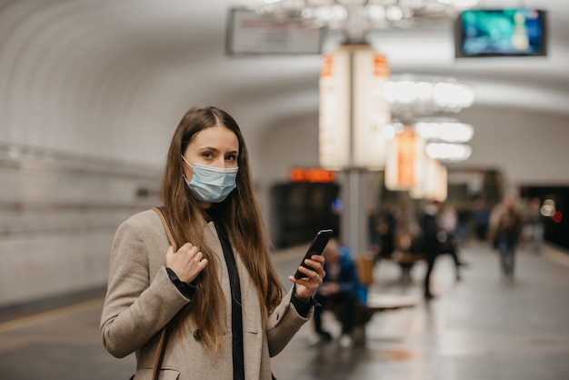 Uma mulher com uma máscara facial médica na estação de metrô