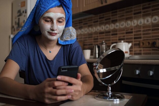Uma mulher com uma toalha azul na cabeça fala via link de vídeo em um smartphone
