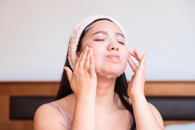 Uma mulher com uma toalha na cabeça e uma toalha na cabeça está lavando o rosto.