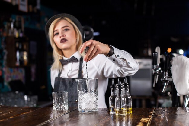 Uma mulher confiante como bartender prepara um coquetel enquanto está perto do balcão do bar