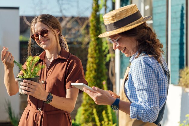 Uma mulher consulta uma jardineira sobre plantas antes de comprá-las em um centro de jardinagem