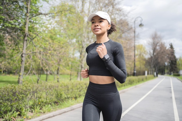 Uma mulher corre fitness usa um rastreador no braço um relógio inteligente  para trens esportivos em roupas esportivas