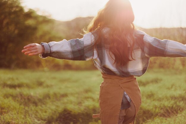 Foto uma mulher corre por um campo de costas para a câmera em um dia de verão com o cabelo comprido e voando ao pôr do sol o conceito de liberdade e harmonia com a natureza foto de alta qualidade