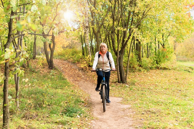 Uma mulher de bicicleta anda na estrada no parque da cidade