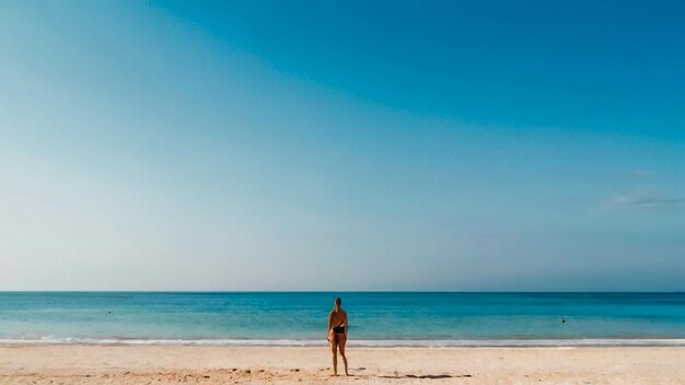 Foto uma mulher de biquíni está na praia em frente ao oceano