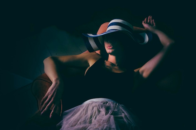 uma mulher de bodysuit com um copo de vinho reflete sobre a vida intrigante com um rosto escondido por um chapéu