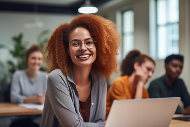 uma mulher de cabelo vermelho está sentada na frente de um laptop com outras pessoas ao fundo