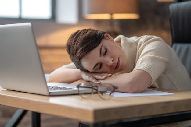 Uma mulher de cabelos escuros cochilando no laptop depois de um dia difícil