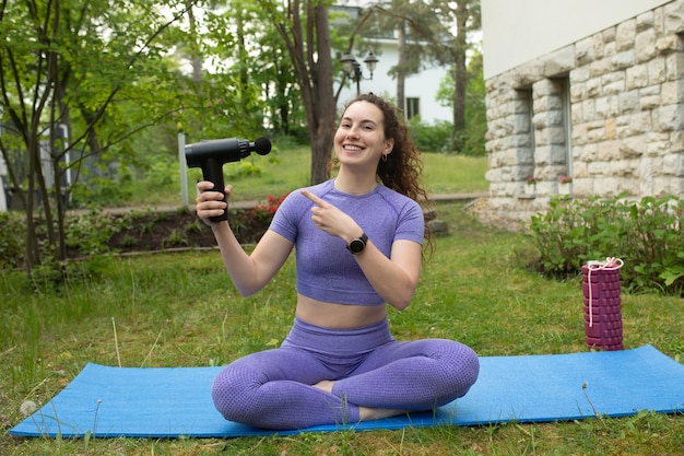 Uma mulher de calça roxa e camisa roxa está sentada em um tapete e aponta para uma arma.