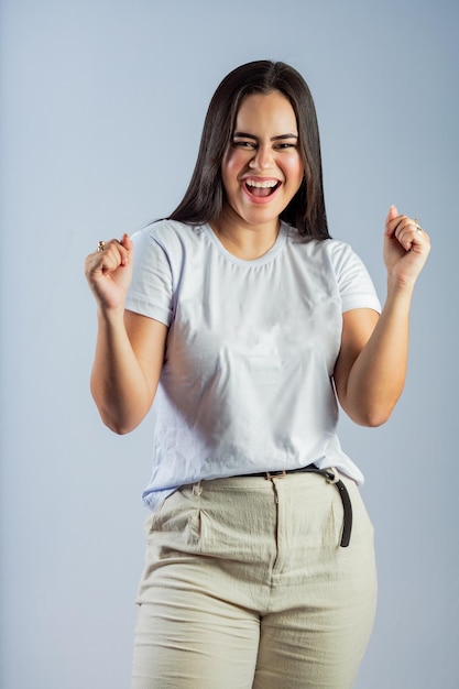 Uma mulher de camisa branca e calça cáqui está comemorando uma vitória.