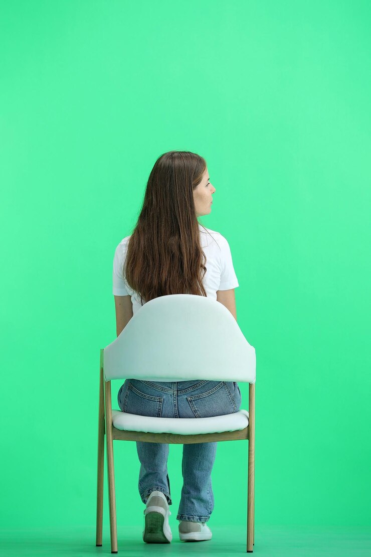 Foto uma mulher de comprimento completo em um fundo verde sentada em uma cadeira