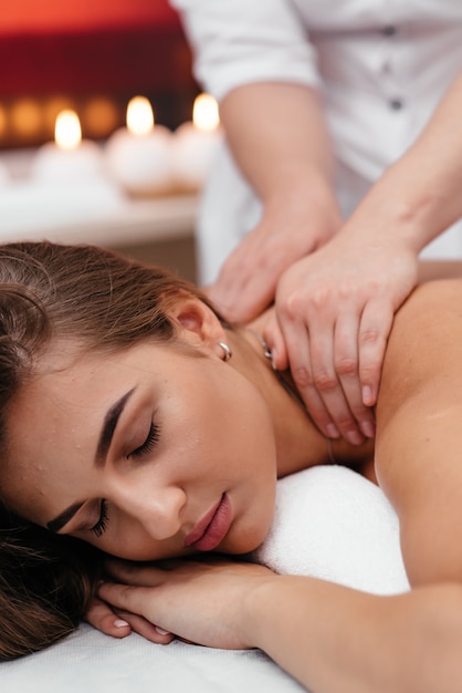 Foto uma mulher de meia idade, deitado sobre uma mesa de massagem em um salão de beleza com pedras quentes nas costas.