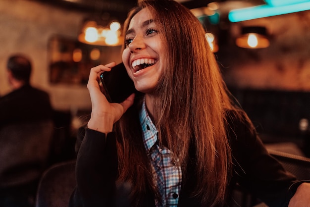 Uma mulher de negócios atraente usando um smartphone enquanto está sentado em um café moderno Retrato de negócios Foco seletivo