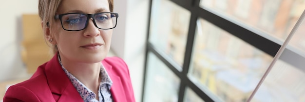 Uma mulher de negócios com óculos no escritório escreve em um quadro um conceito de educação em close-up em