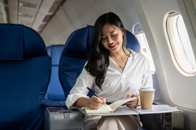 Uma mulher de negócios está fazendo anotações em seu caderno enquanto voa para outra cidade para uma reunião de negócios