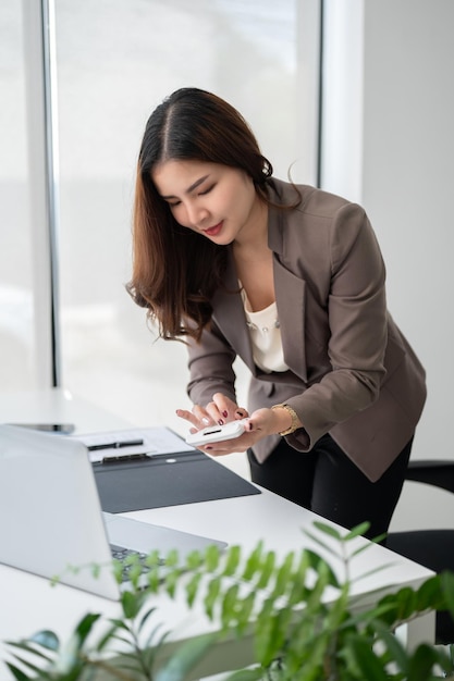 Uma mulher de negócios inclinando-se sobre uma mesa e usando uma calculadora trabalhando no escritório