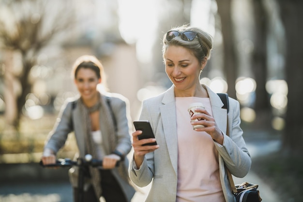 Uma mulher de negócios madura surfando em um smartphone enquanto vai trabalhar.