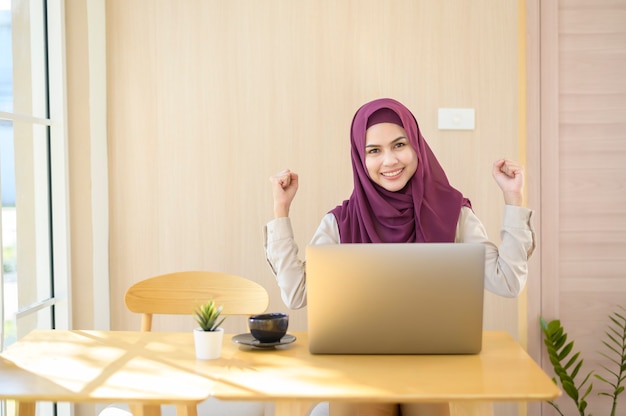 Uma mulher de negócios muçulmana usando hijab e trabalhando com seu laptop em uma cafeteria
