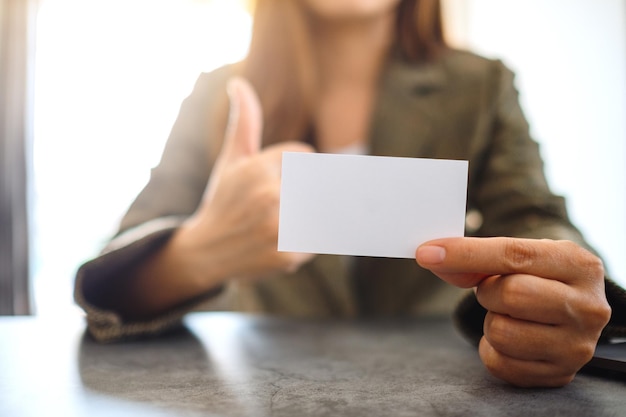 Uma mulher de negócios segurando e mostrando um cartão de visita em branco vazio enquanto faz a maquiagem para mostrar um bom sinal