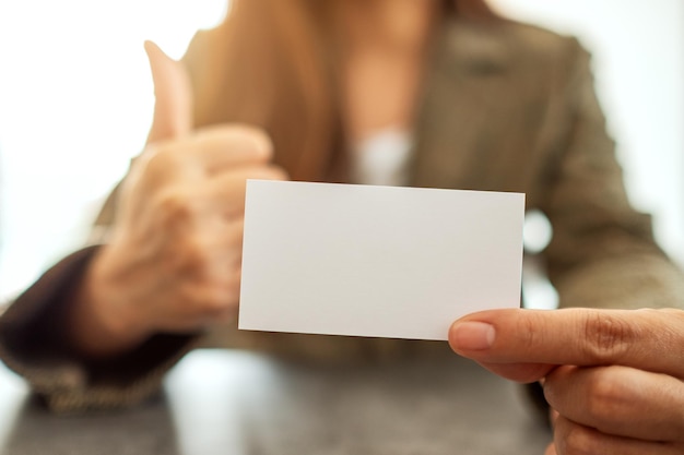 Uma mulher de negócios segurando e mostrando um cartão de visita em branco vazio enquanto faz a maquiagem para mostrar um bom sinal