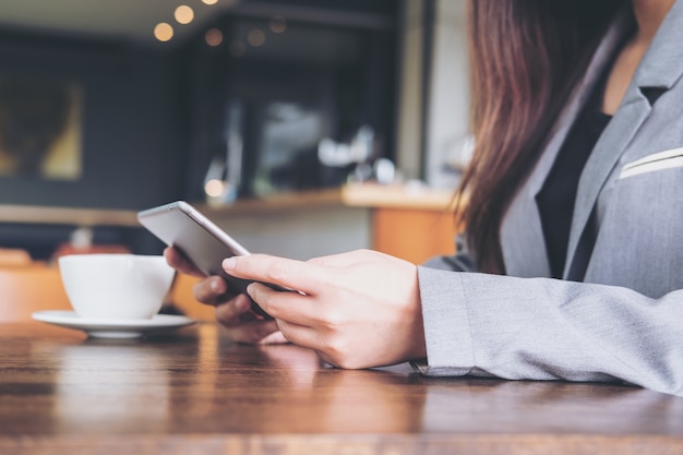 Uma mulher de negócios segurando e usando um comprimido com copo de café na mesa de madeira no café