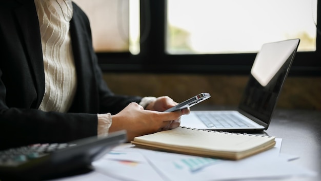 Uma mulher de negócios usando seu smartphone em sua mesa de escritório