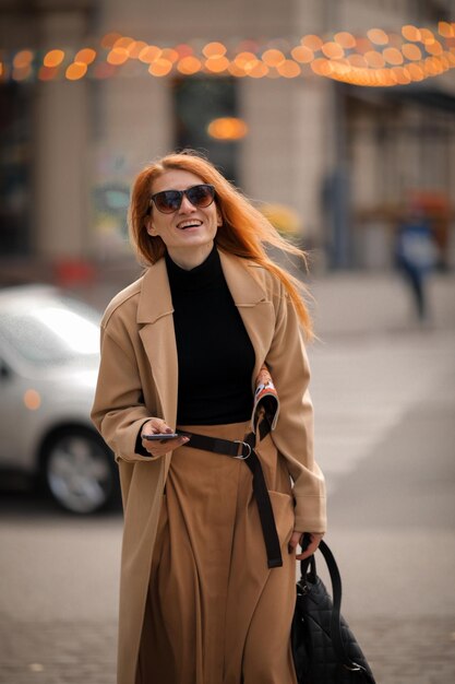 uma mulher de óculos escuros caminha pela rua. caminhar na cidade de outono
