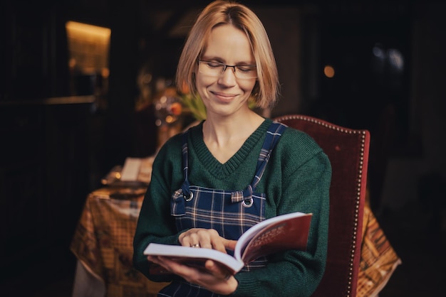 Uma mulher de óculos está lendo um livro Mulher atraente de meia-idade, quarenta anos, leitura de descanso em casa