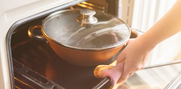 Uma mulher de perto abre o forno e leva comida fresca para casa