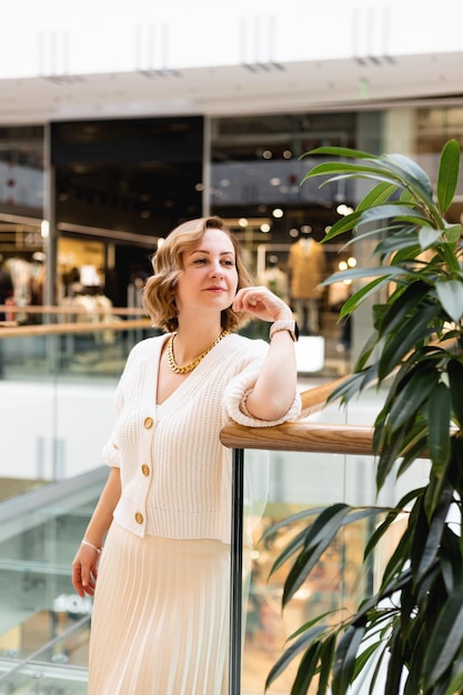 Uma mulher de roupas leves de negócios está perto de uma flor