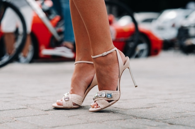 Uma mulher de sapatos de salto alto com diamantes artificiais na cidade. pés bonitos em close-up de sapatos.