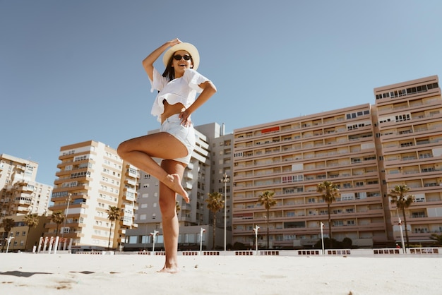 Uma mulher de shorts brancos fica na praia em frente a um hotel em ibiza