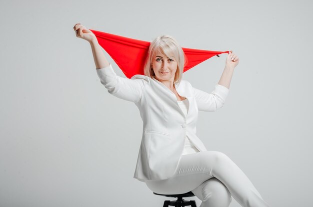 uma mulher de terno branco com um lenço vermelho em um fundo branco