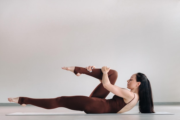 Uma mulher de terno marrom faz ioga em uma sala de ginástica Estilo de vida saudável treinamento de fitness autocuidado