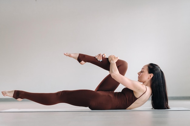 Uma mulher de terno marrom faz ioga em uma sala de ginástica Estilo de vida saudável treinamento de fitness autocuidado