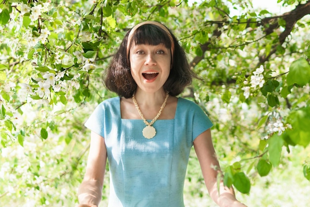 Uma mulher de vestido azul com macieiras em flor no jardim primavera