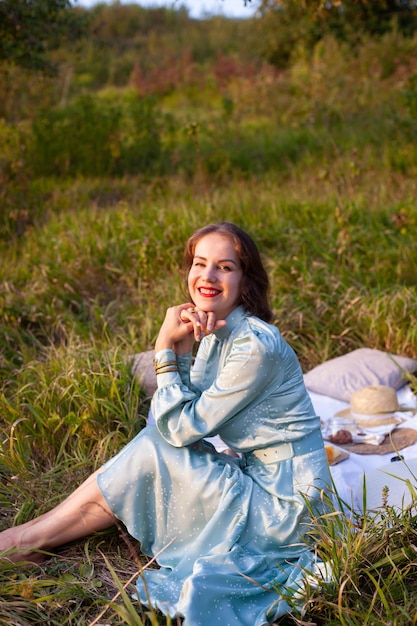 Uma mulher de vestido azul senta-se em um piquenique em um parque com vista panorâmica