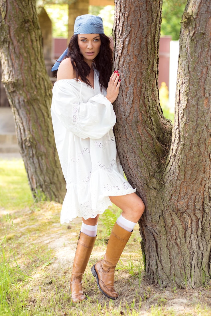 Foto uma mulher de vestido branco está apoiada em uma árvore