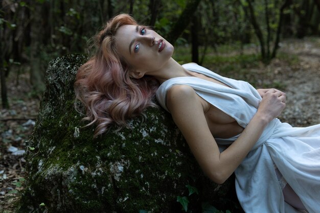 Uma mulher de vestido branco no meio da floresta