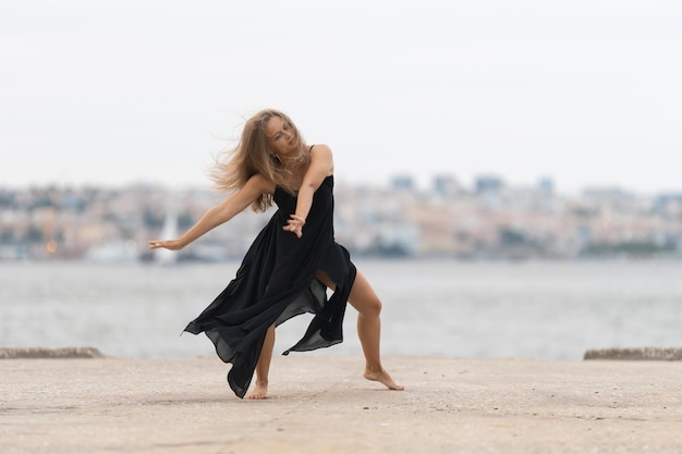 Uma mulher de vestido preto dançando no cais